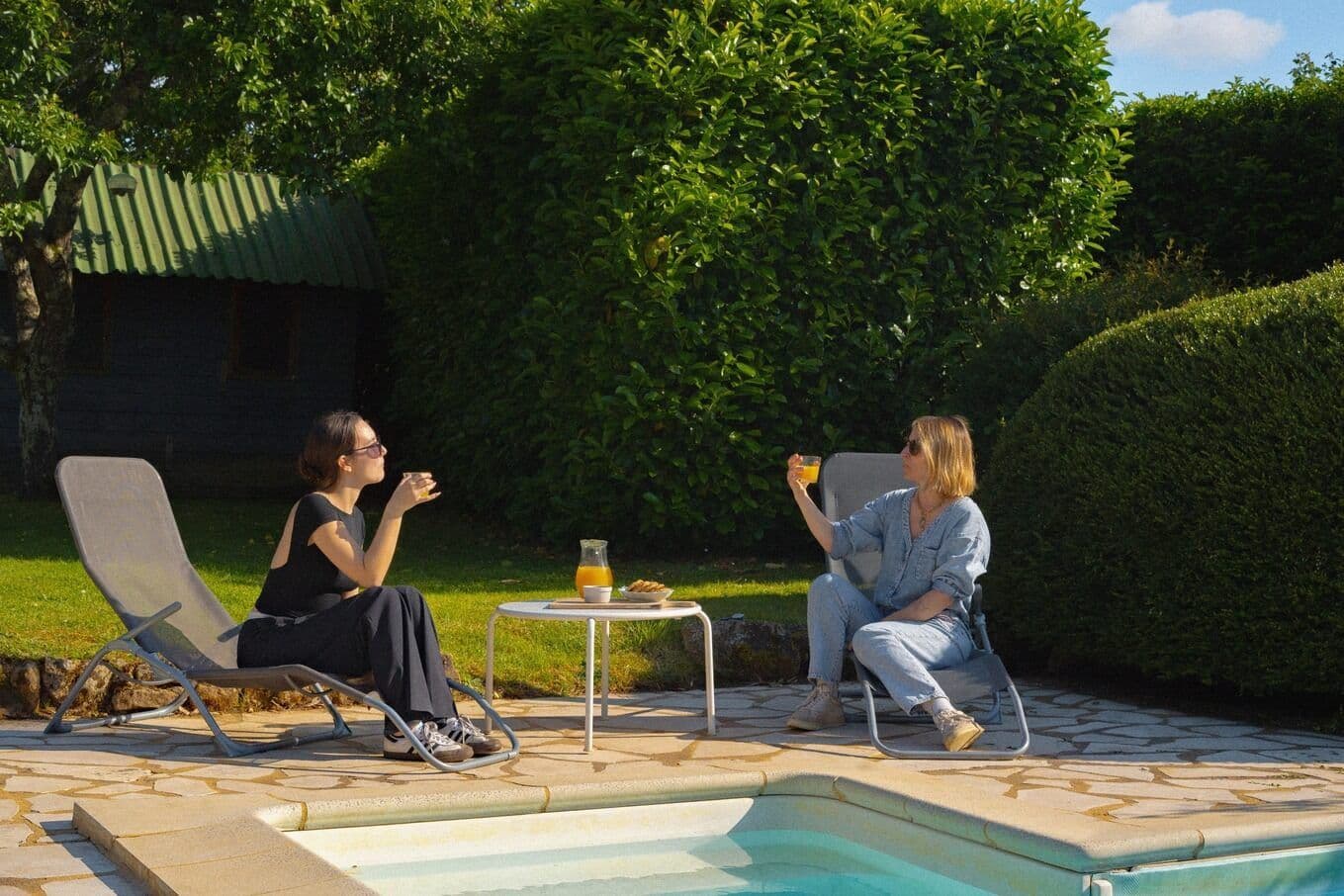 Deux personnes prenant le goûter au bord de la piscine du gîte "le bonheur dans notre pré" en Dordogne.